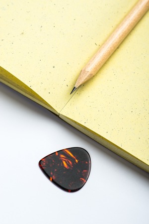 Yellow notepad with pencil and mediator on white surfaceの写真素材