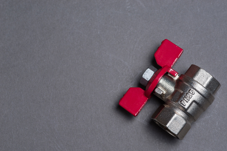 Water valve with red handle on grey backgroundの写真素材