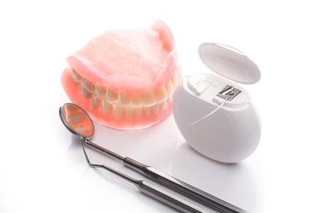 Teeth model with dental floss and mouth mirror on white surfaceの写真素材