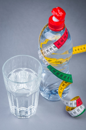 Bottle and glass of fresh still water with measuring tapeの写真素材
