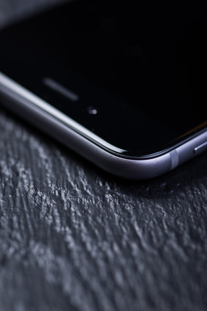 Black smart-phone on a black wooden tableの写真素材