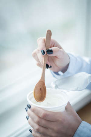 A cup of fresh yogurt in young woman's handsの写真素材