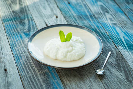 Plate with fresh yogurt on rustic wooden tableの写真素材