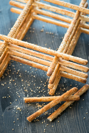 Bunch of homemade grissini breadsticks in a glass jar on wooden table