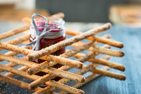 Bunch of homemade grissini breadsticks in a glass jar on wooden table
