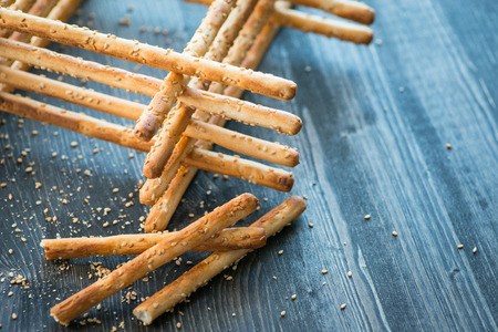 Bunch of homemade grissini breadsticks in a glass jar on wooden tableの写真素材