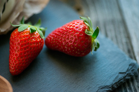 Two fresh strawberries on a rustic stone plateの写真素材