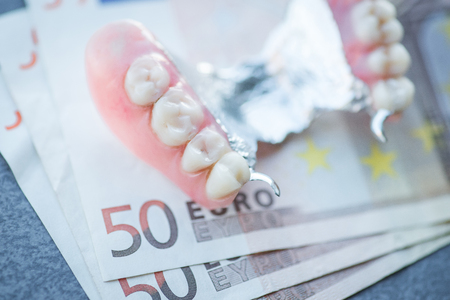 Artificial replacement teeth with money on a dark surfaceの写真素材