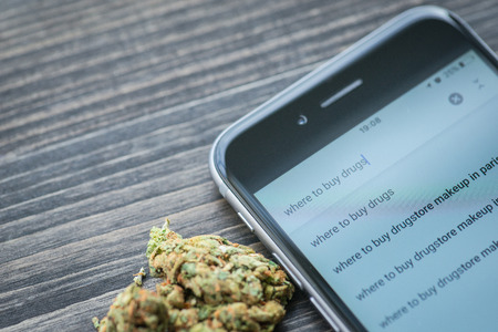 Phone and weed on a rustic wooden table