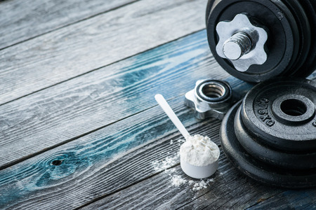 Classic dumbbell with protein powder on wooden tableの写真素材