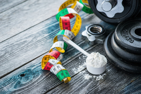 Classic dumbbell with protein powder on wooden tableの写真素材