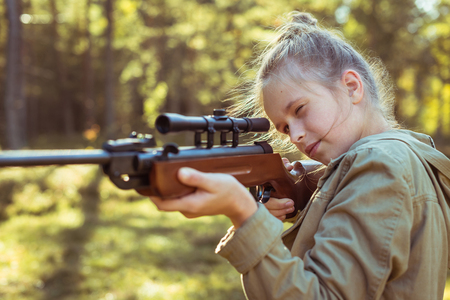 Young girl shooting from the air rifle in the forestの写真素材