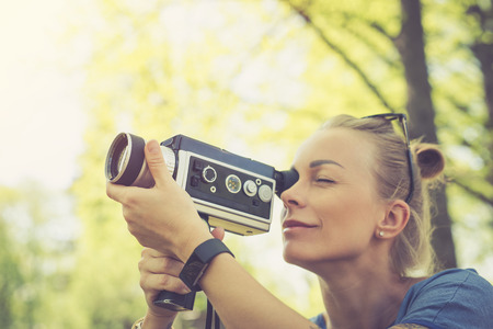 Summer. Young beautiful woman with vintage camera in the parkの写真素材