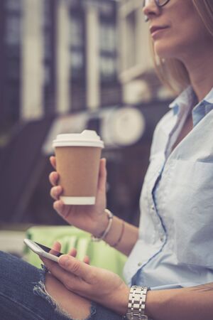 Beautiful young girl in the city drinking coffeeの写真素材