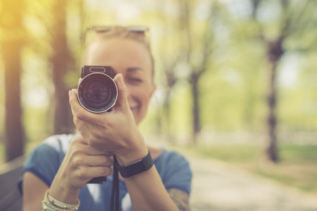 Summer. Young beautiful woman with vintage camera in the parkの写真素材