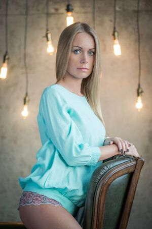 Beauty portrait. Portrait of a beautiful woman on the armchair by the wall with vintage bulbsの写真素材