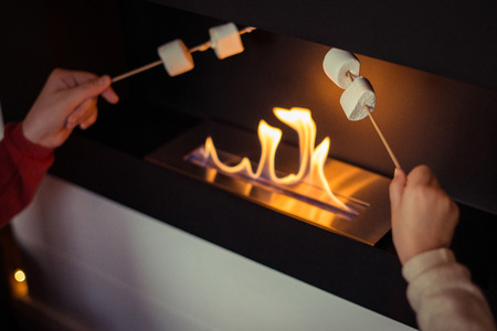Christmas. Two sisters cooks the marshmallow on christmas by the fireplace