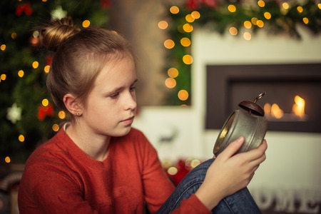 Christmas. Small girl is holding the vintage clock on christmasの写真素材
