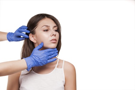 Beautiful girl model. Plastic surgery touching the beautiful face of a woman. Beautician applies...