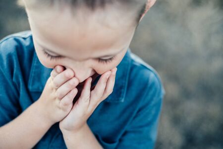 LITTLE BOY SMILING WITH HANDS OVER FACEの写真素材