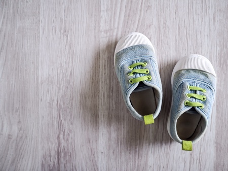 Cute little baby shoe on wood floor background, top view.の素材