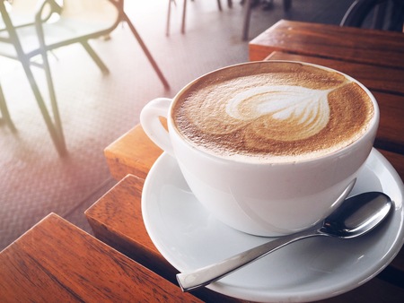 A cup of cappuccino coffee on wooden table in the morningの写真素材