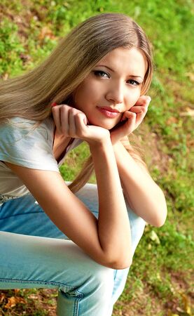Young beautiful blond girl sitting on the grass の写真素材