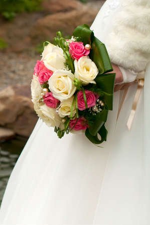 Bouquet of white and rose roses in the bride's handの写真素材