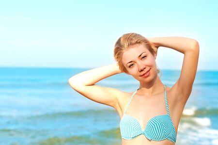 A young beautiful blond girl is staying near the ocean in the morningの写真素材