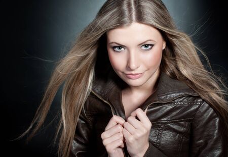 Beautiful blond girl on the black background with blowing hair の写真素材