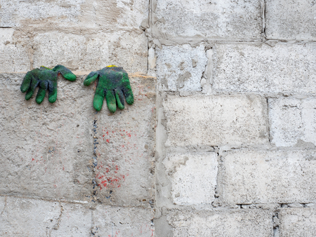dirty gloves drying on the concrete wallの写真素材