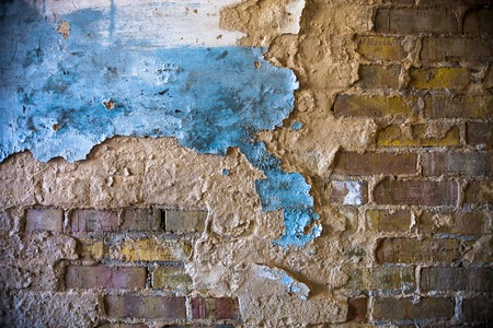 Old brick wall with the damaged blue-painted plaster.の写真素材