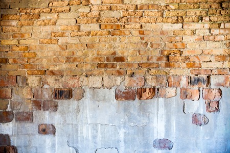 Old brick wall with the damaged plaster.