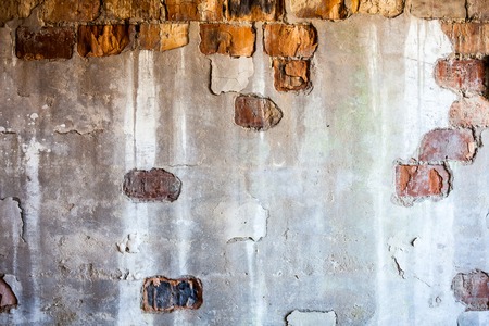 Old brick wall with the damaged plaster.の写真素材