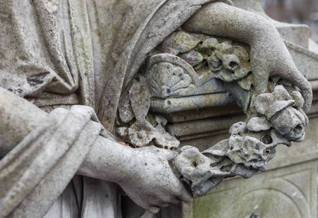 Woman's hands holding the wreath. Old cemetery marble sculpture detail.の写真素材
