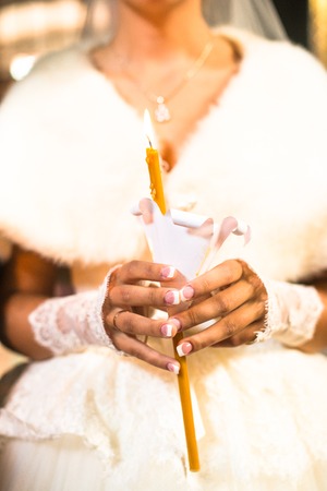 Bride holding the candle during the wedding ceremony in orthodox church. Close up.の写真素材