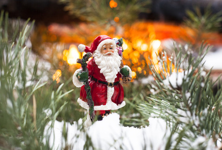Toy Santa Claus standing on the fir tree branch against the fire background.の写真素材