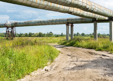 Elevated section of the pipelines above the dirt roadの写真素材