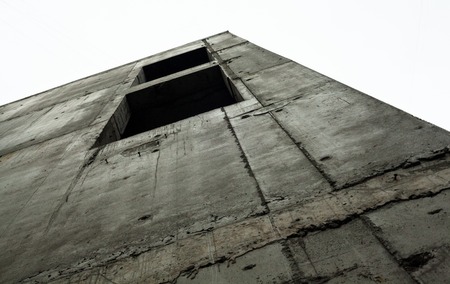 Concrete wall with window openings of the unfinished building against the white skyの写真素材