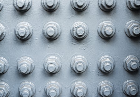 Gray painted metal surface with bolts and hexagon nuts.の写真素材