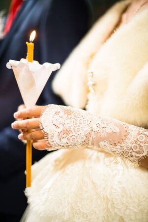 Wedding ceremony in orthodox church. Bride and groom holding the candles. Close up.の写真素材