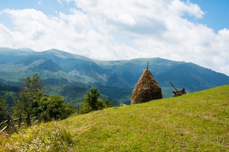 Haystack and wooden cart against the summer landscape in the Ukrainian Carpathiansの写真素材