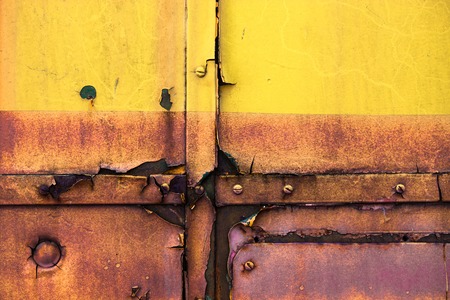 Rusty metal surface with cracked yellow paint.の写真素材