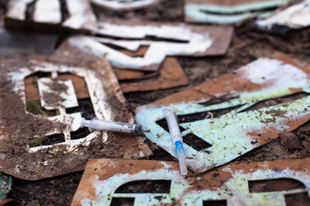 Used syringes on the old metal stencils on the ground.の写真素材