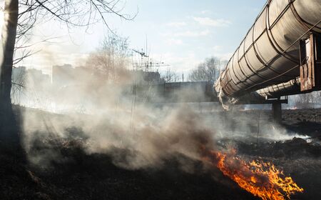 Fire near the pipelines. High-rise city buildings in the background.