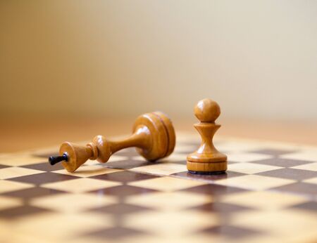 Pawn wins a victory over the king. Wooden chess pieces on the chessboard. Chess game.の写真素材