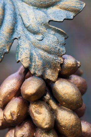 Metal grapes bunch and leaf. Forged ornament. Painted in bronze color. Close-up.の写真素材