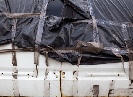 Crashed car wrapped in black plastic sheeting. Automobile after the accident covered with polythene....