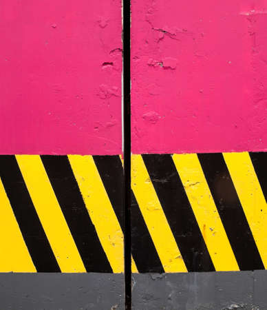 Pink concrete columns with black and yellow safety stripes.