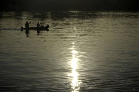 boy and his mother paddling on a kayak, reflection in waterの写真素材